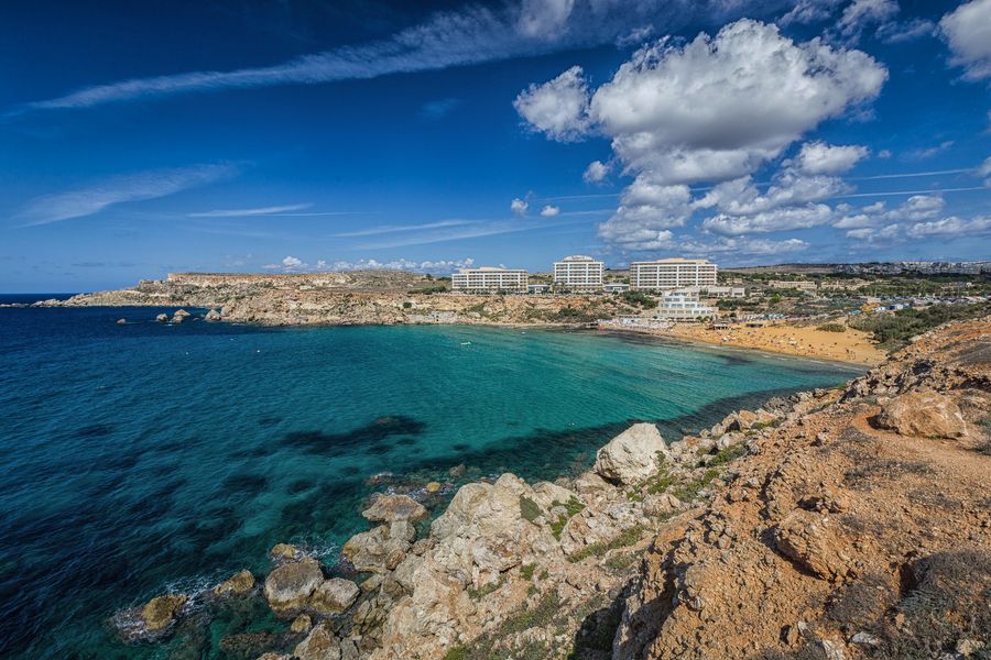 A goregous view of golden bay showing crystal blue waters, the sandy beach and a deep blue sky.